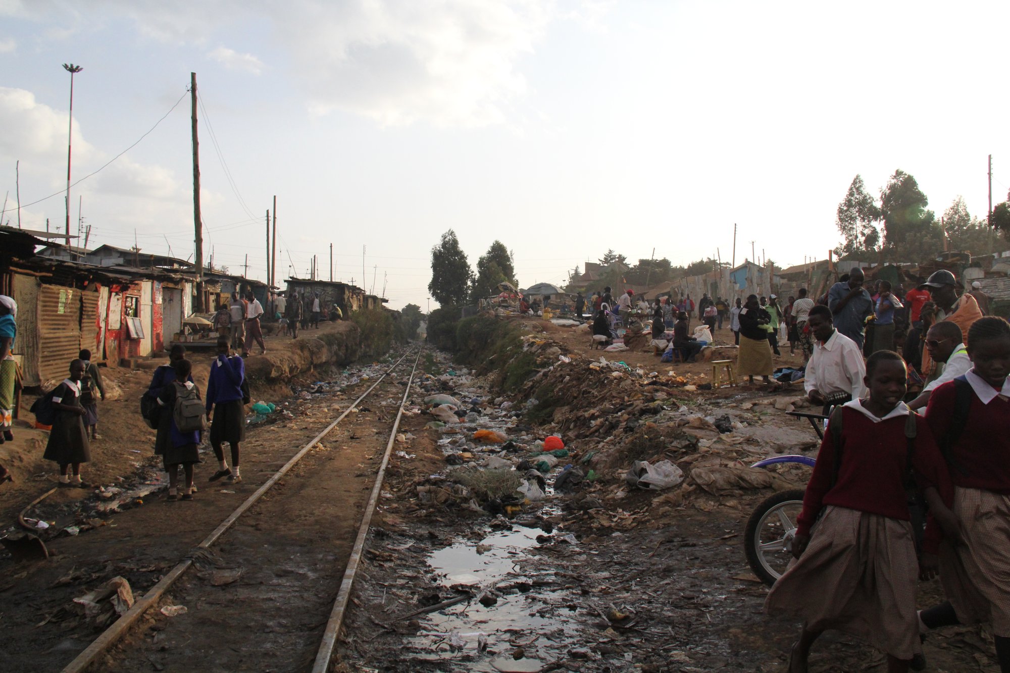Children in school uniforms walking along the railway through Kibera